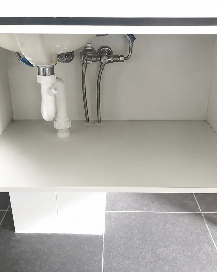 Cleared bathroom vanity cupboard with visible valves, flexible hoses and waste pipe for a Property Protection Audit.