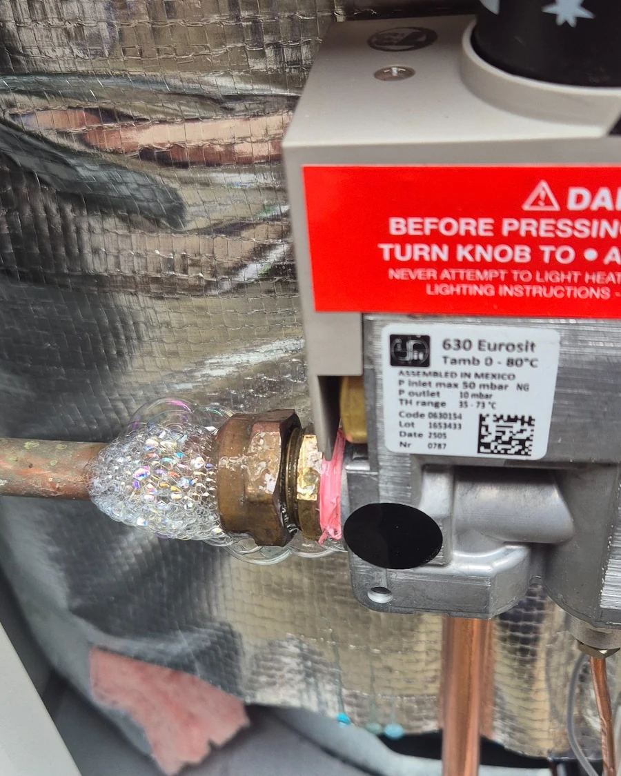 Gas leak detection solution bubbling at a residential gas appliance connection, confirming a leaking fitting.