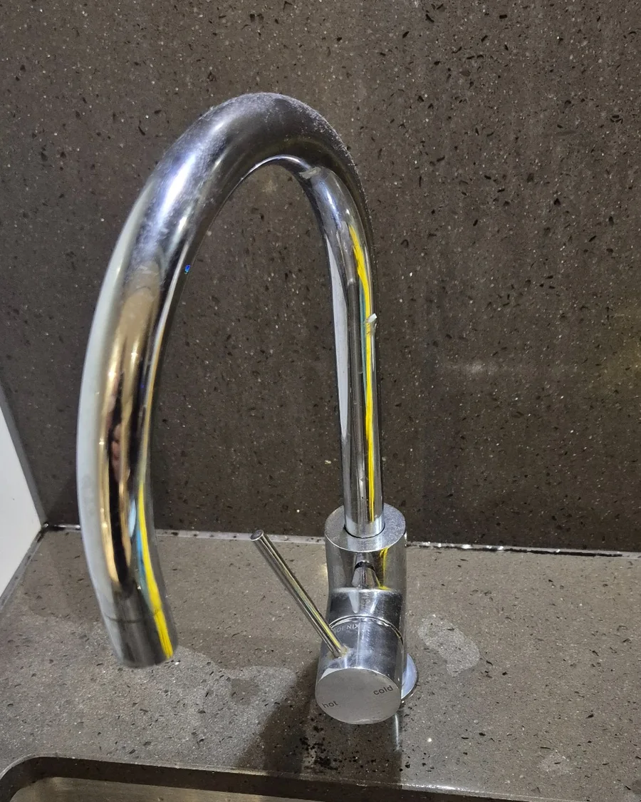 Leaking kitchen mixer tap with visible water pooling around the tap base at a Melbourne CBD property.