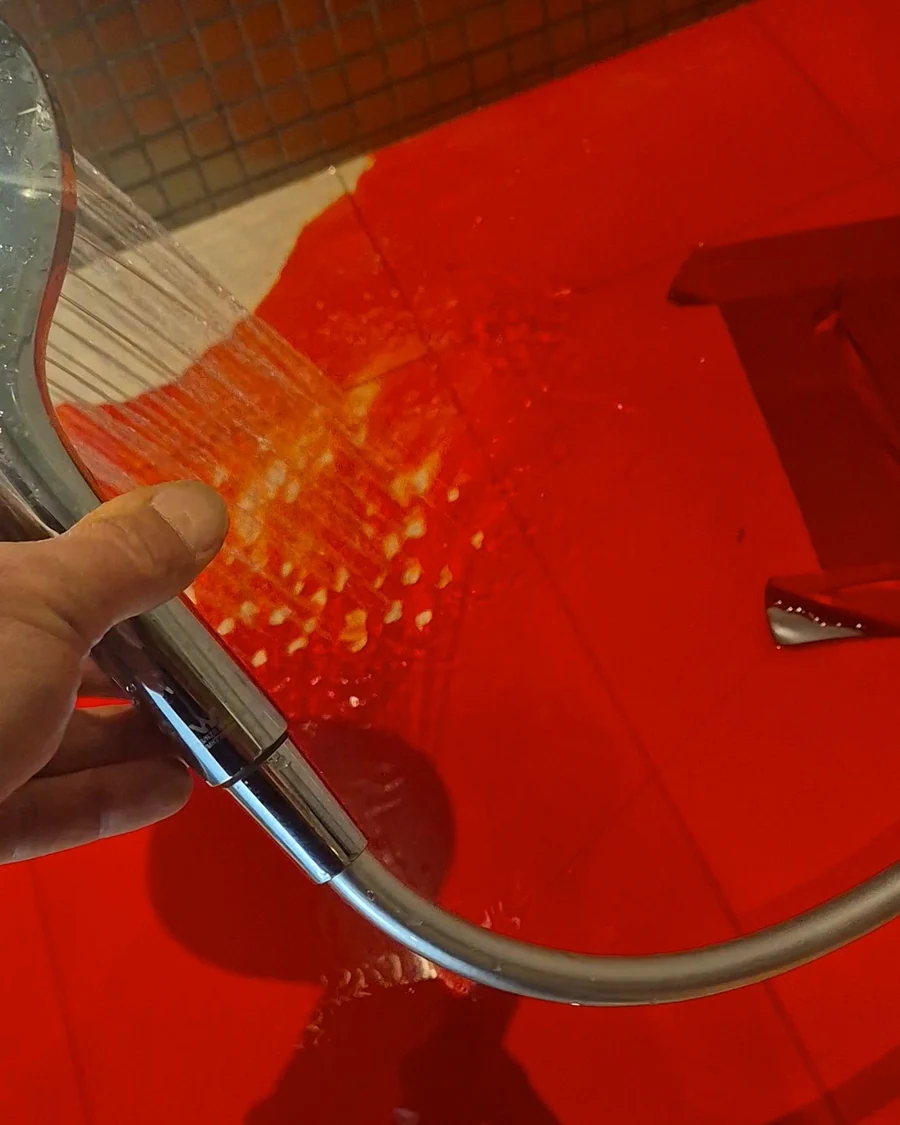 Red dye flood testing a shower base to investigate waterproofing integrity and possible water leakage.