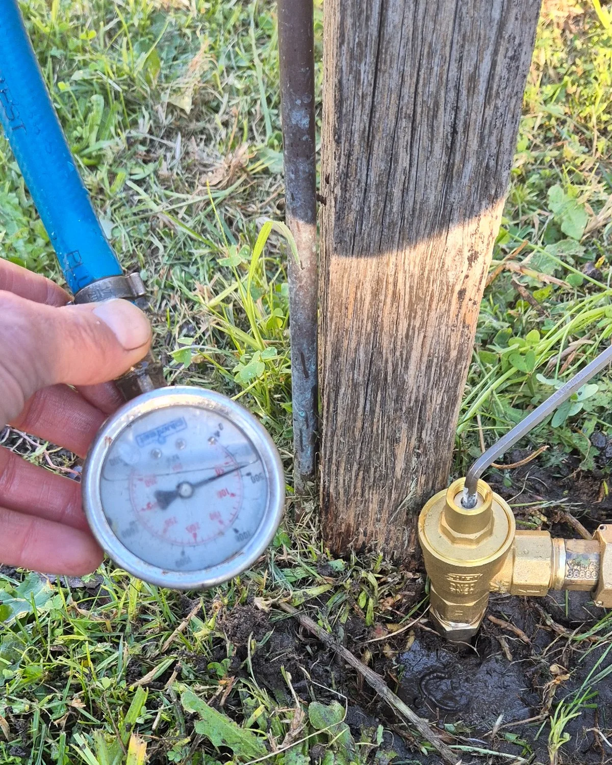Water pressure gauge beside a newly installed pressure reducing valve during water hammer diagnosis and pressure control work.