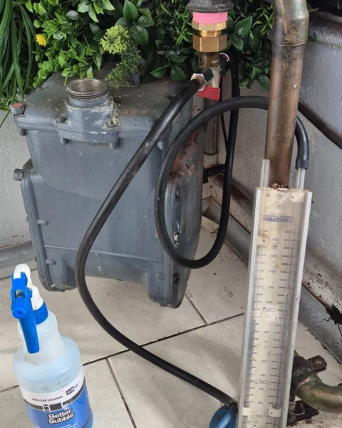 Residential gas meter set up for gas leak detection using a manometer and leak detection solution.