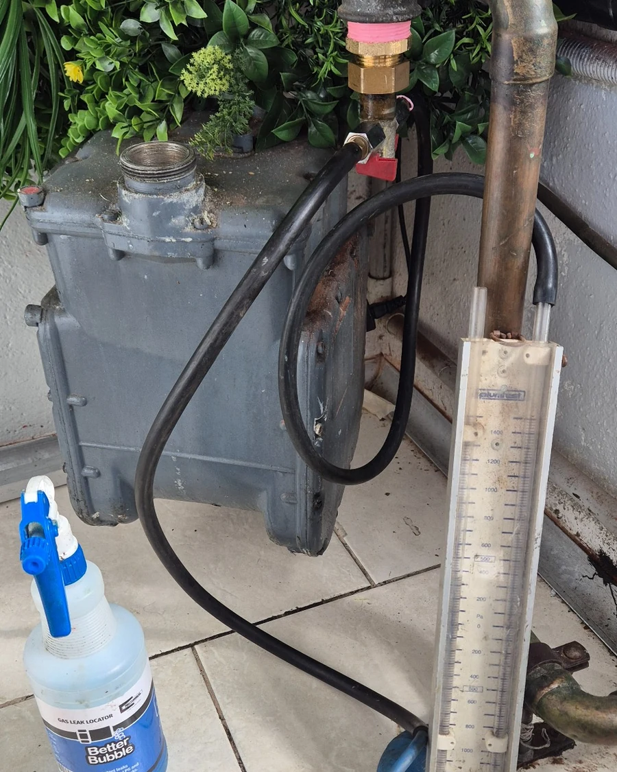 Residential gas meter set up for gas leak detection using a manometer and leak detection solution.