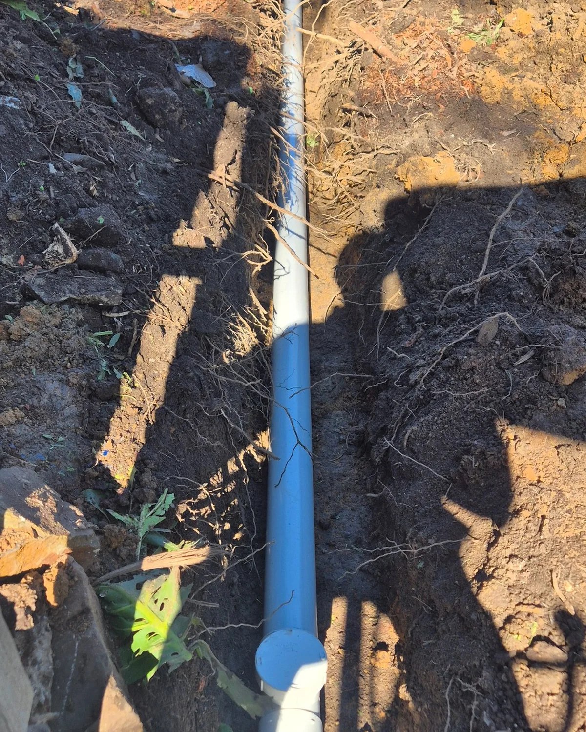 New UPVC stormwater drain installed through an excavated backyard trench.