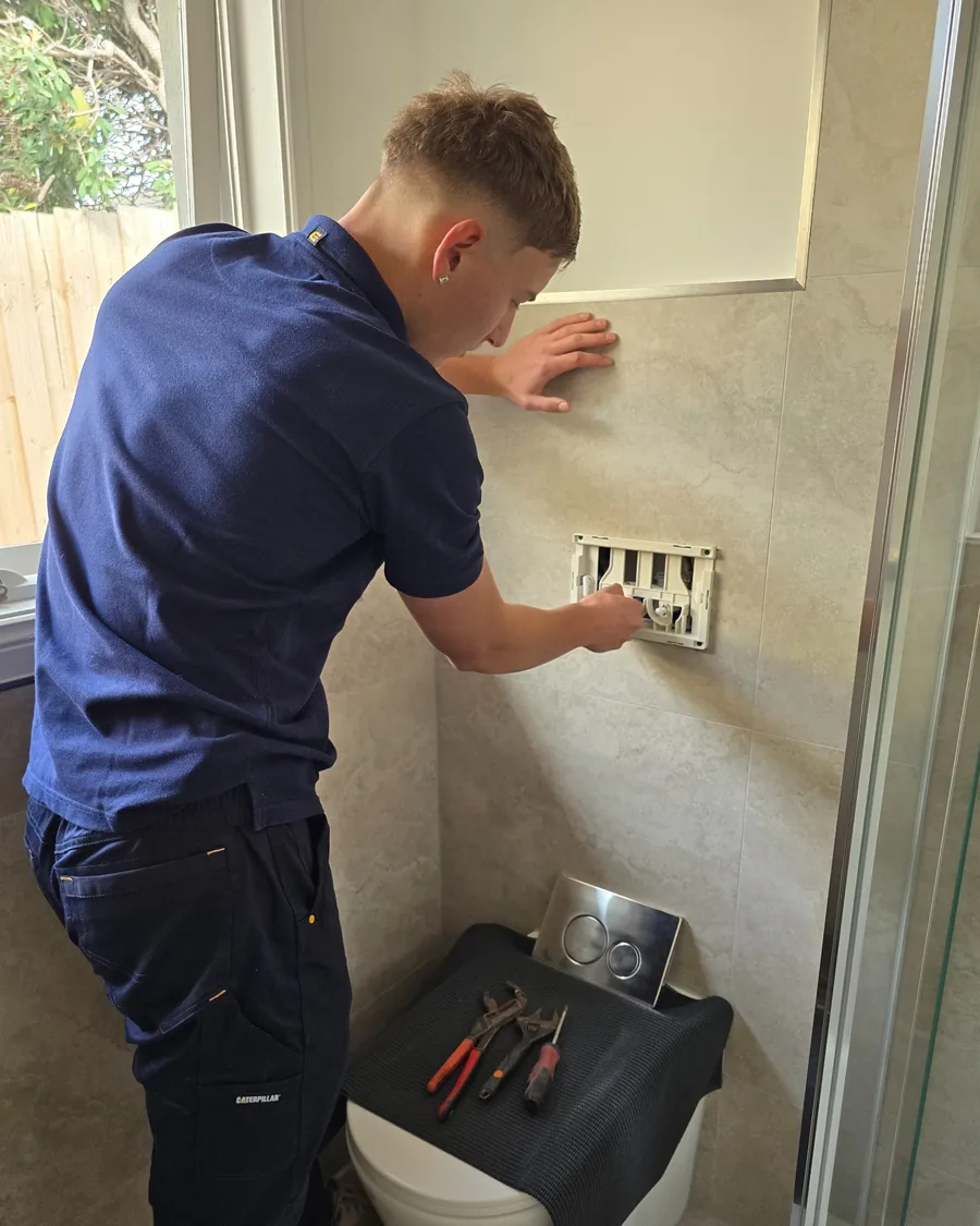 Your Choice Plumbers plumber servicing a concealed toilet cistern through the wall access opening at a client’s home.