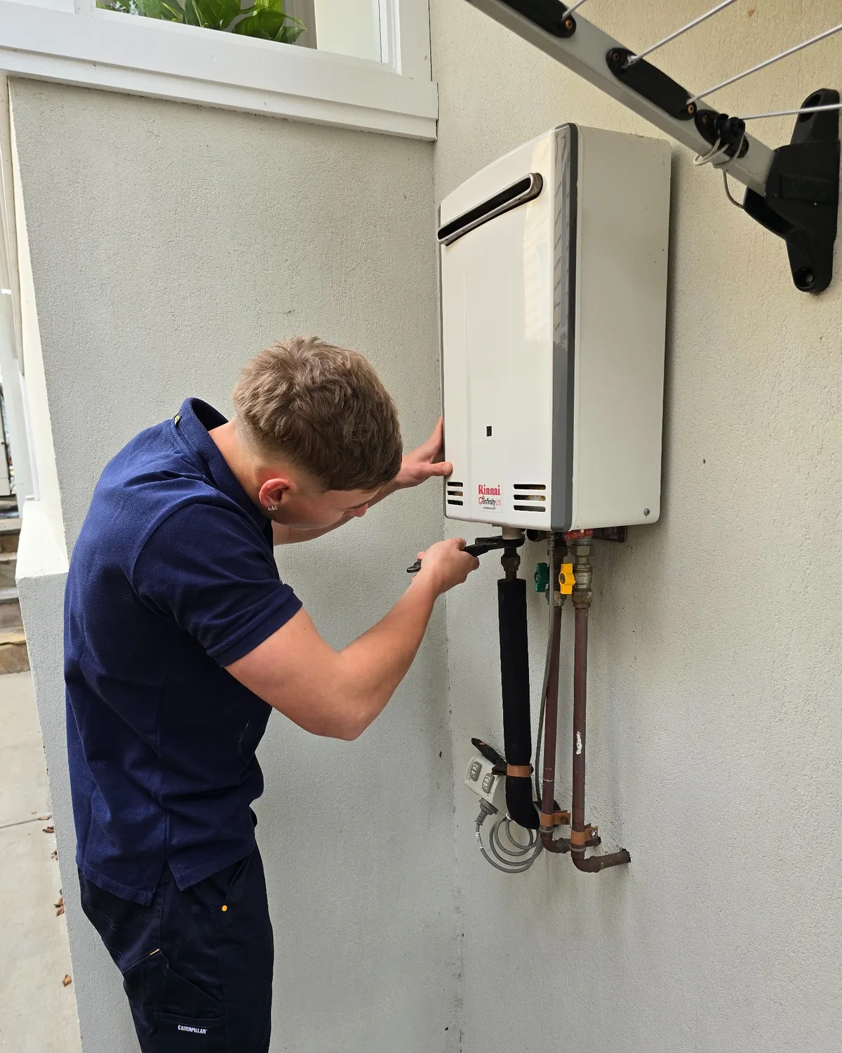 Your Choice Plumbers plumber inspecting a Rinnai continuous flow hot water system at a client’s home.