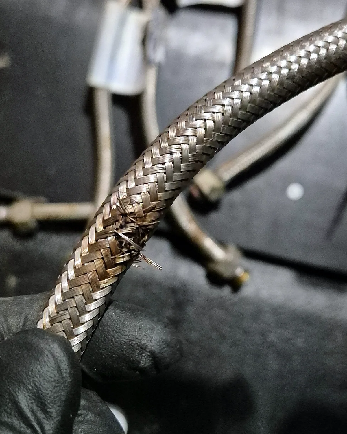 Damaged braided flexible hose showing frayed stainless-steel braid and visible deterioration.